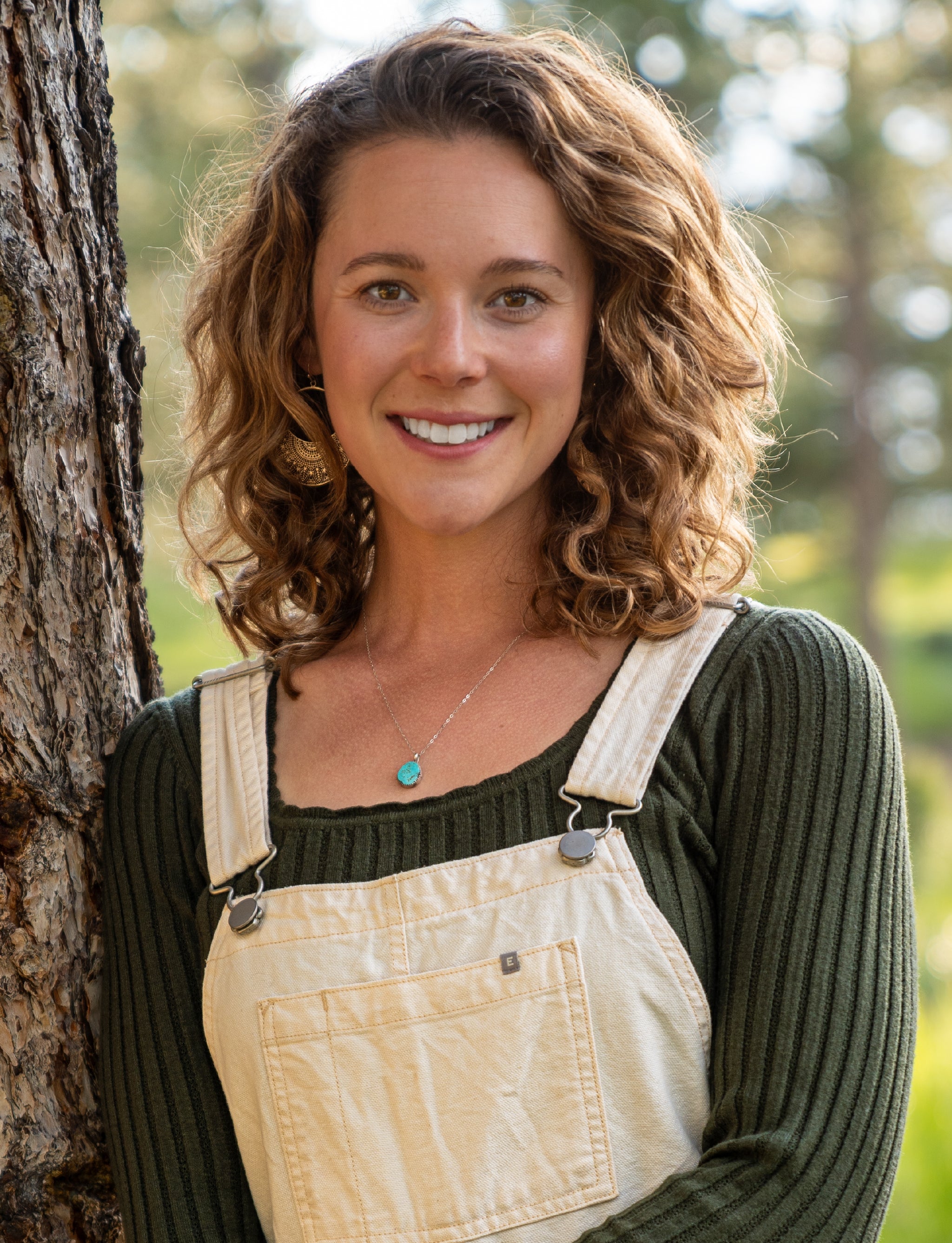 Picture of Abby Rogers, leaning against a tree and smiling into the camera.