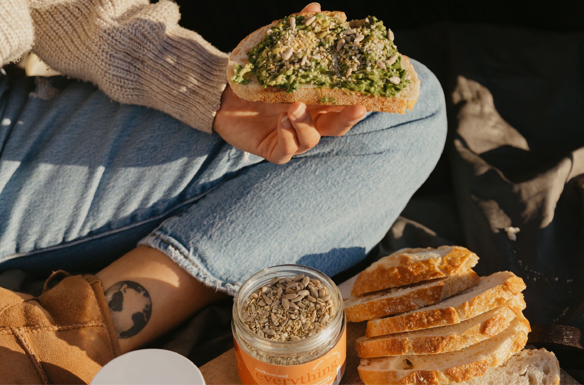 A hand holding a piece of toast sprinkled with seeds.